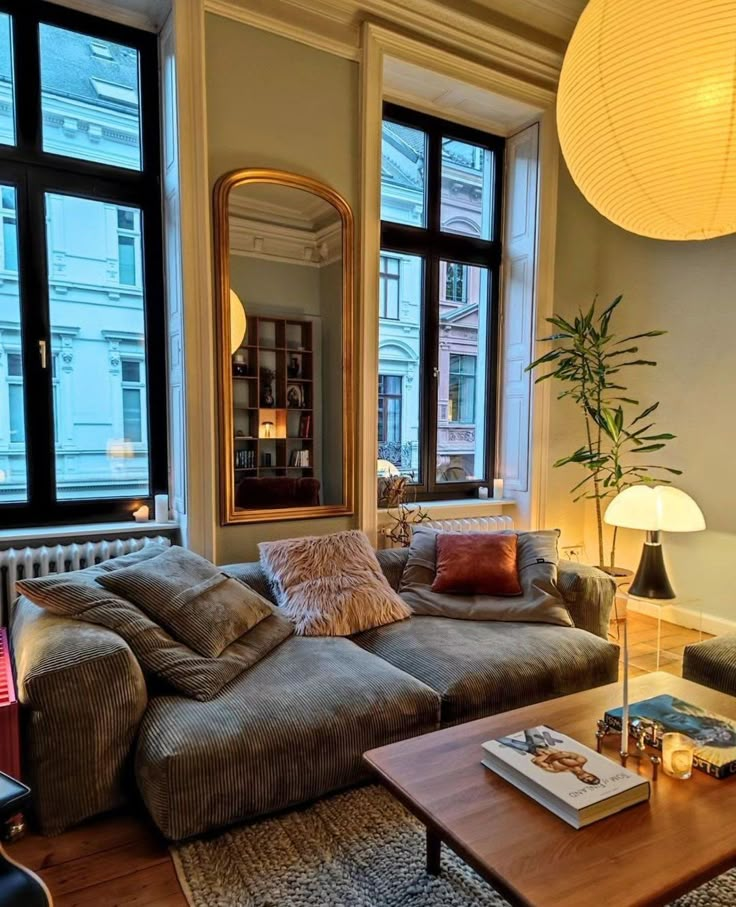 a living room filled with furniture and lots of windows next to a lamp on top of a table