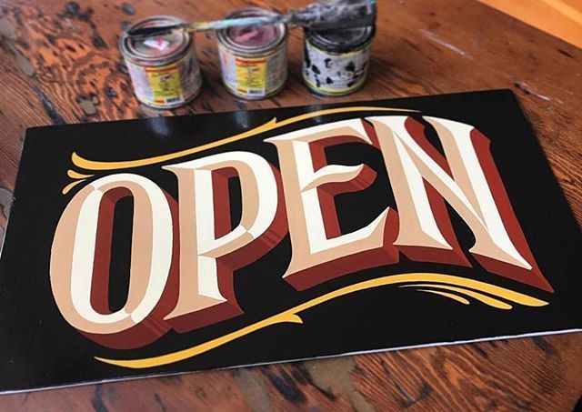 an open sign on a table with cans of beer