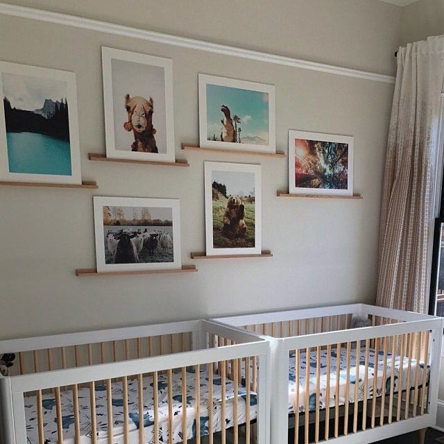 two baby cribs with pictures on the wall above them in a nursery room