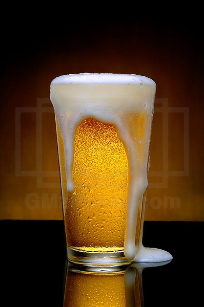 a glass filled with liquid sitting on top of a table next to a black surface