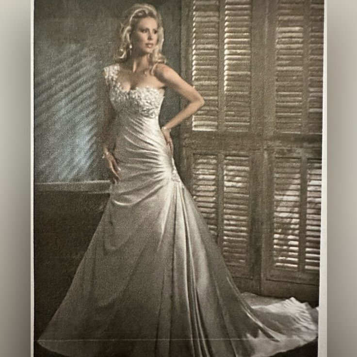 a woman in a wedding dress standing next to a window with shutters on it