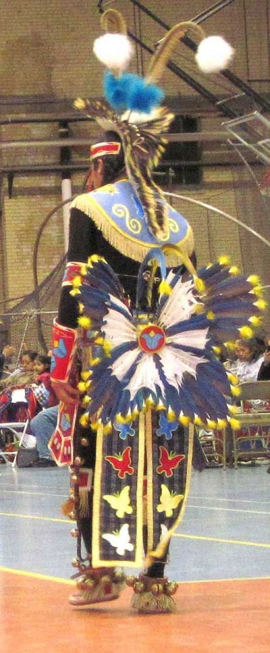 an elaborately dressed dancer is performing in the middle of a court with people watching