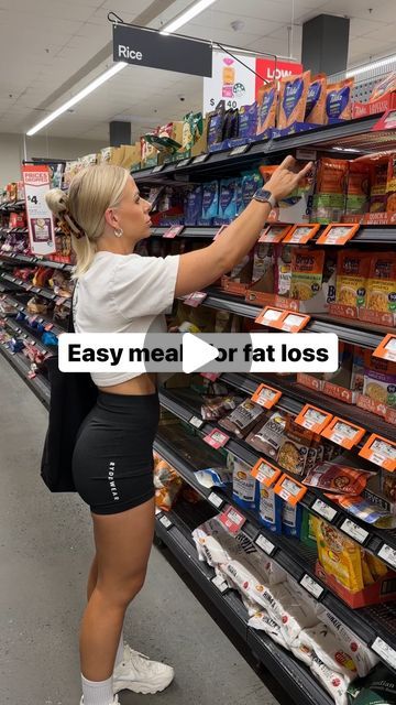 a woman is shopping in a grocery store and pointing to the shelf with her hand