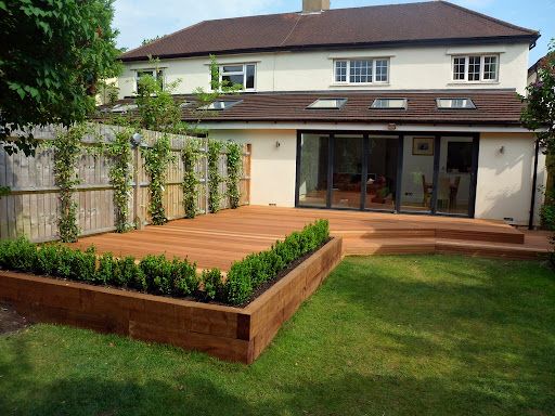 a large wooden deck in the middle of a yard with plants growing on it's sides