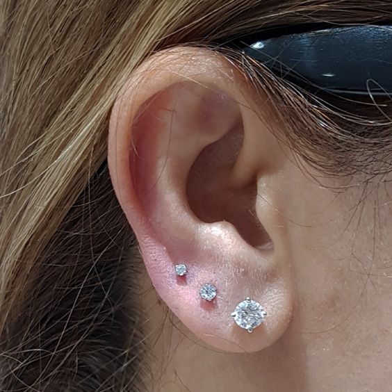 a close up of a person's ear with three diamond studs on it