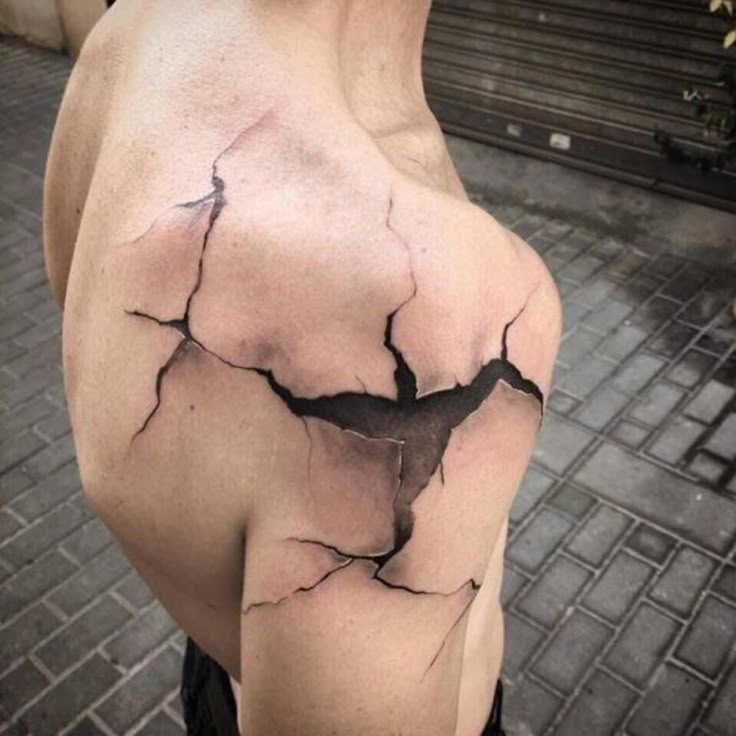 a man's shoulder with a black and white cracked up piece of paper on it