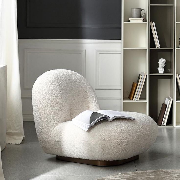 a white chair with a book on top of it in front of a bookshelf