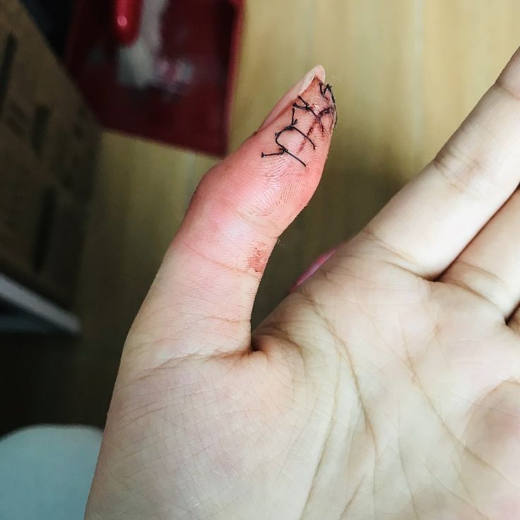 a person's left hand with a small tattoo on the middle finger and two fingers