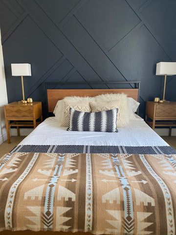 a bed with two nightstands next to it and a wall painted in dark blue