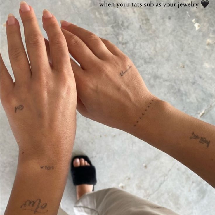 two people with matching tattoos on their arms, one holding the other's hand