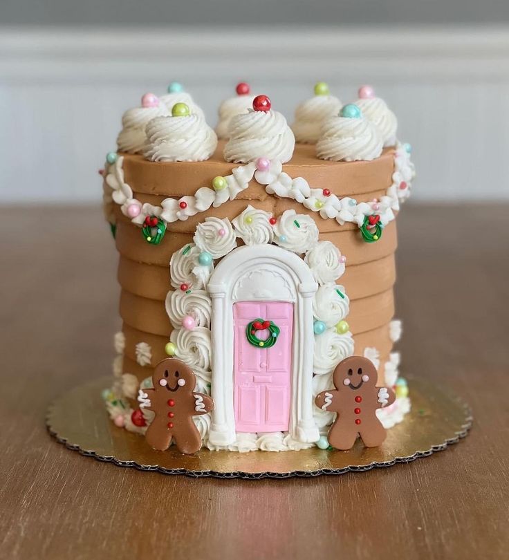 a gingerbread house decorated with icing and decorations on a wooden table next to a white wall