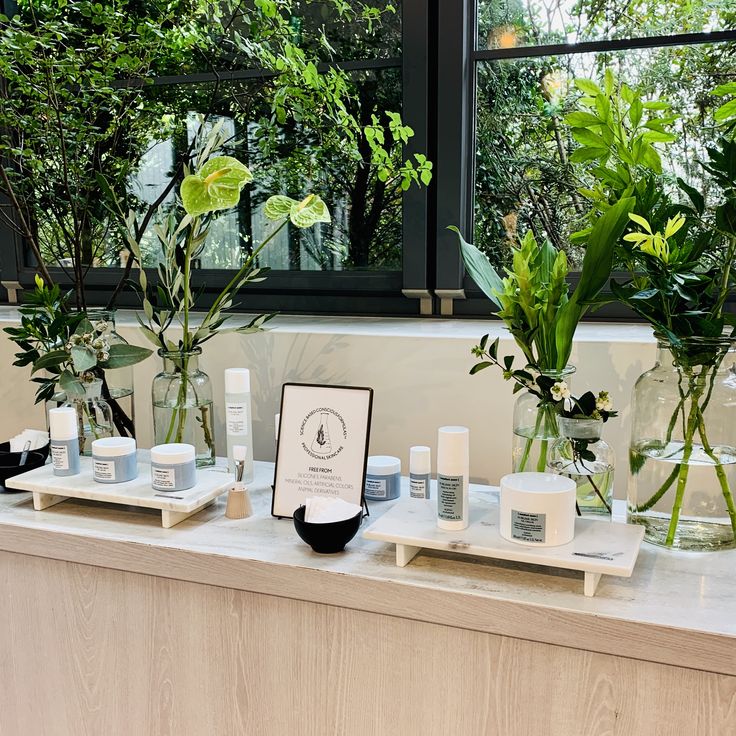 several vases with plants in them on a counter next to a sign that says the plant shop