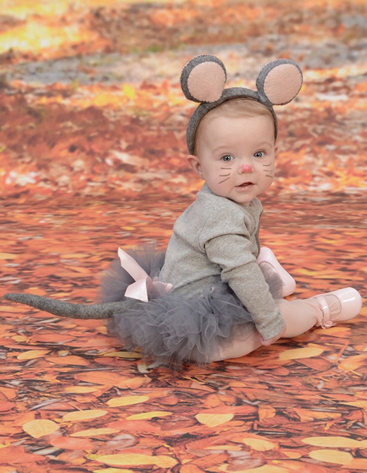 a baby wearing a mouse costume sitting on the ground