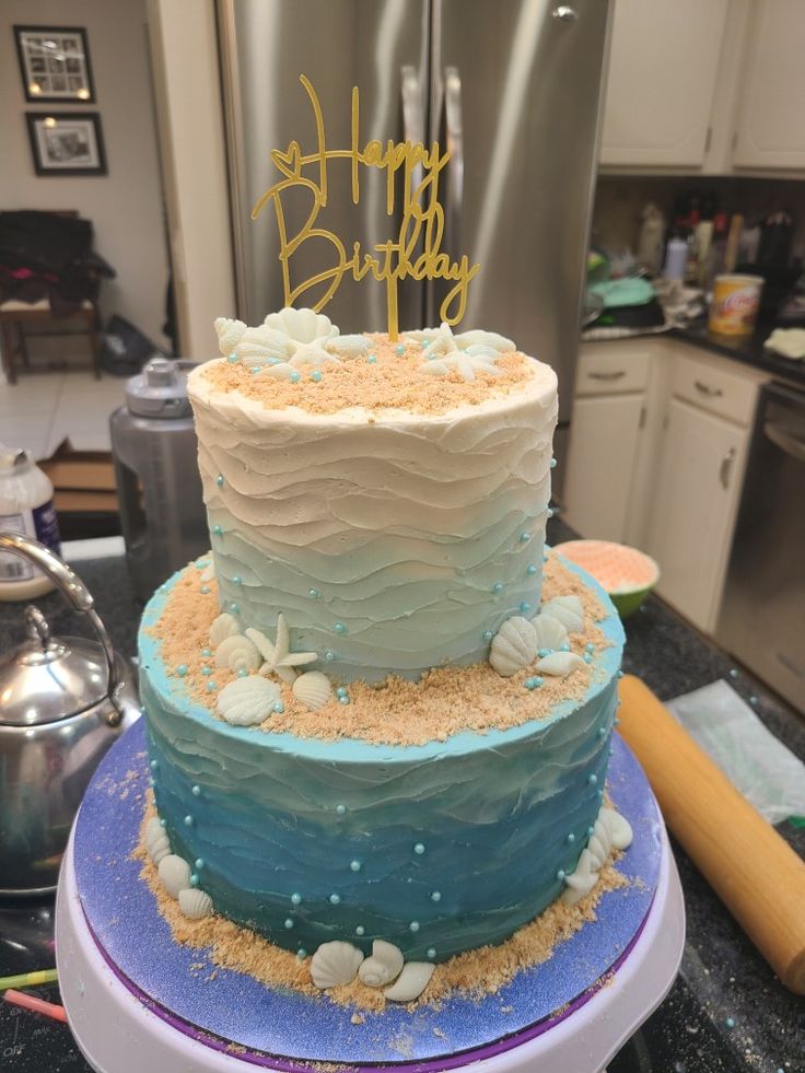 a three tiered cake with blue frosting and white icing, on top of a counter