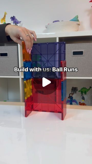 someone is playing with a building set on the floor in front of some toy bins