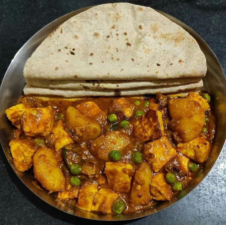 a metal bowl filled with food on top of a black counter next to a tortilla