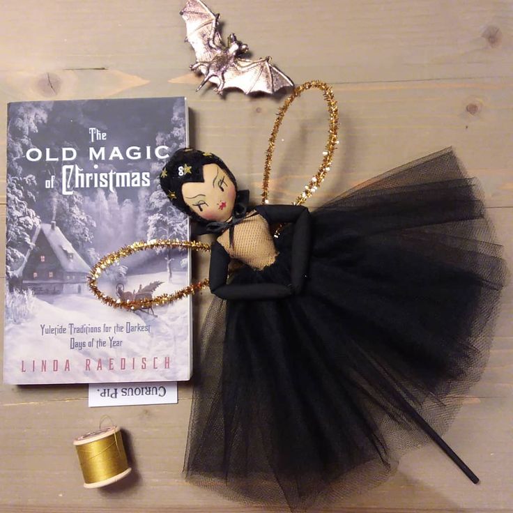 the doll is wearing a black tutu and gold necklace