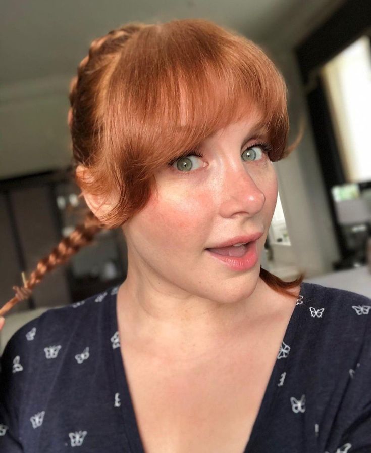 a woman with red hair and blue eyes holding a toothbrush in her right hand