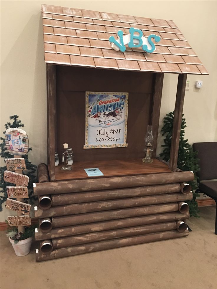 a wooden structure with logs stacked on top of it in front of a christmas tree