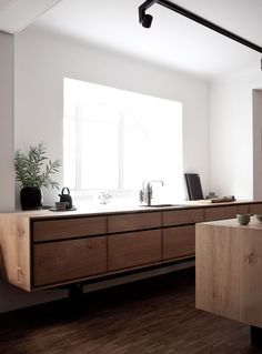 a kitchen with wooden cabinets and white walls, along with a potted plant on the counter