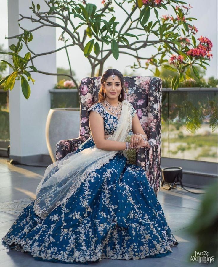 a woman sitting in a chair wearing a blue and white dress with flowers on it