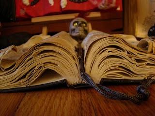 an open book sitting on top of a wooden table next to a cat figurine