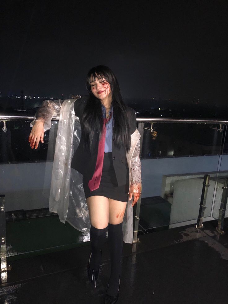 a woman in short shorts and boots standing on a balcony at night with an umbrella over her head