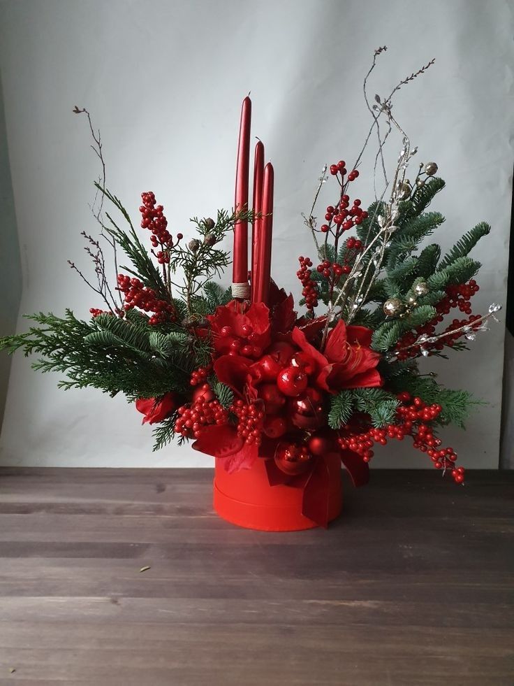 a red candle holder filled with greenery and candles