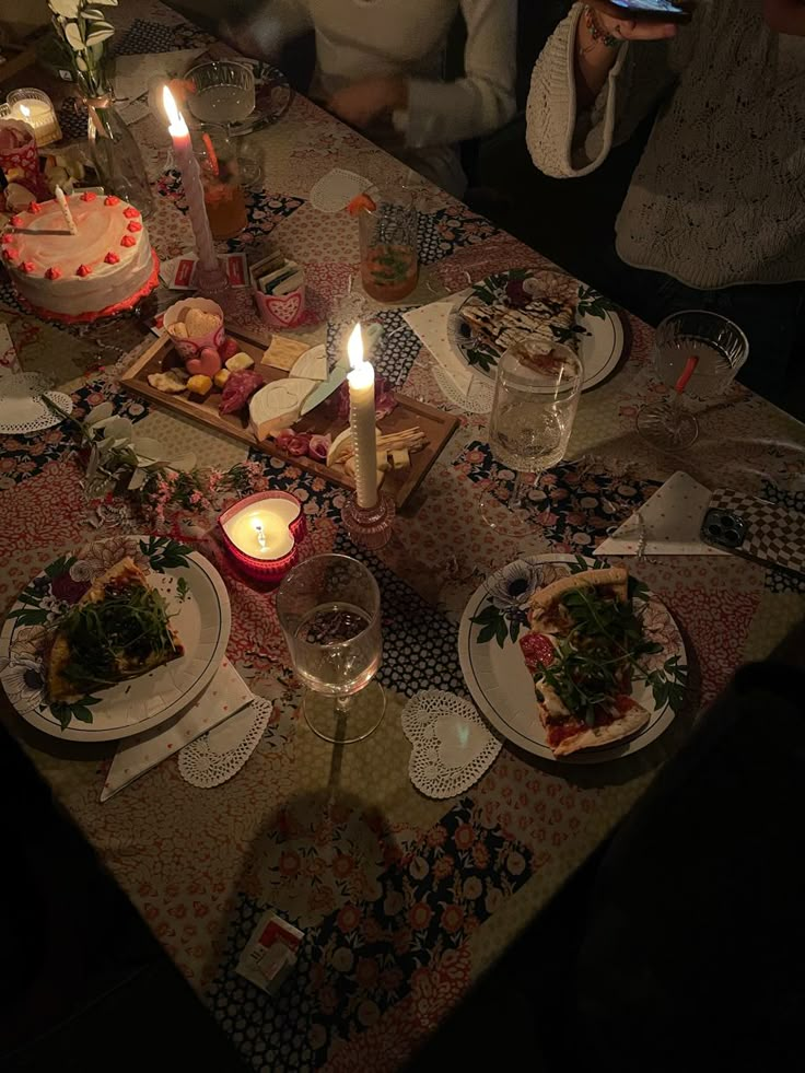 people sitting at a table with food and candles