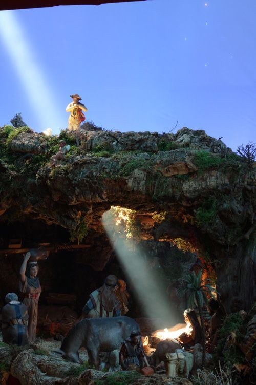 an outdoor nativity scene with figurines and light beams coming from the cave