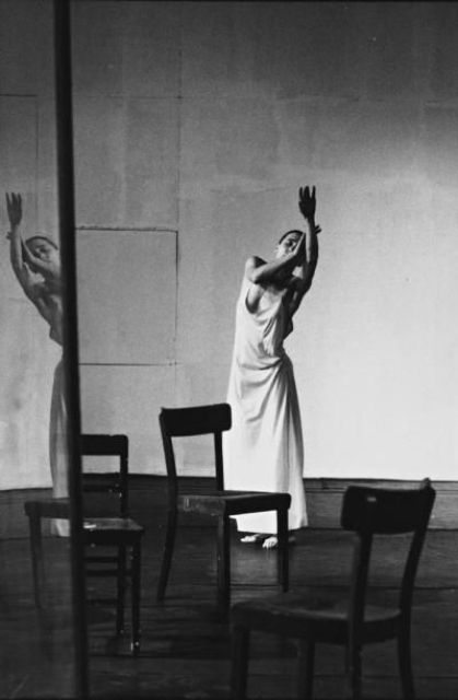 a black and white photo of a woman reaching up