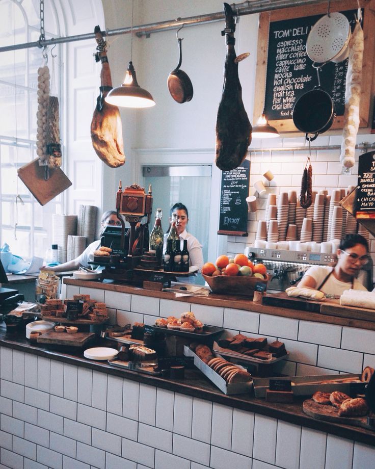 people are standing at the counter in a restaurant with many food items hanging from the ceiling