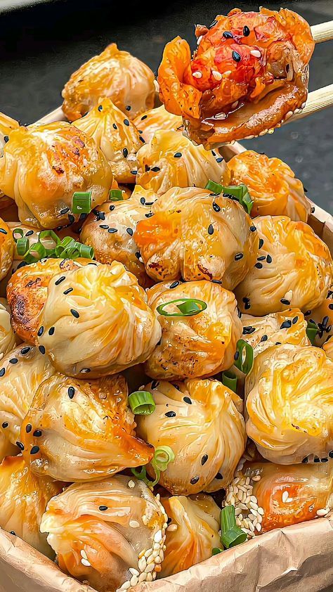 a wooden bowl filled with dumplings covered in sesame seeds and garnishes