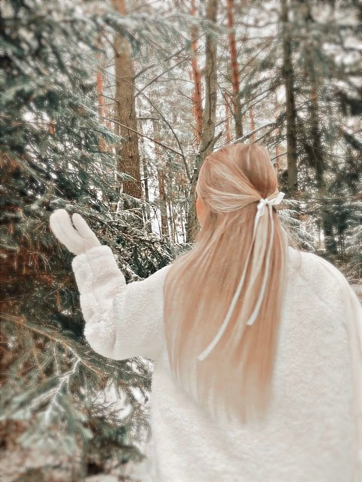 a woman with long red hair standing in the woods holding her hand out to someone