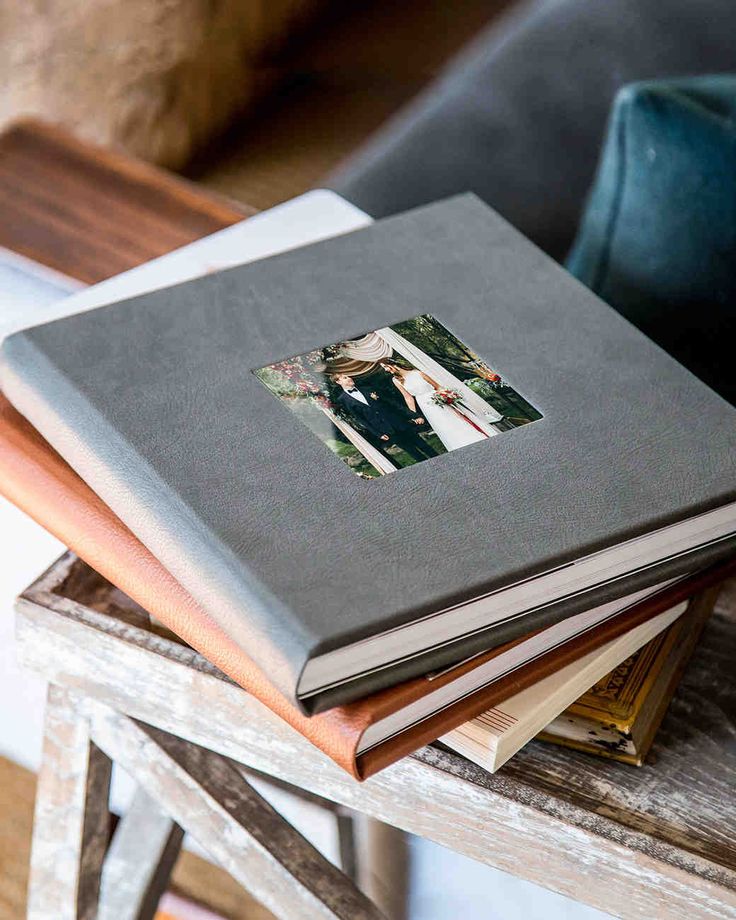 a photo album sitting on top of a wooden table next to a blue chair and pillow