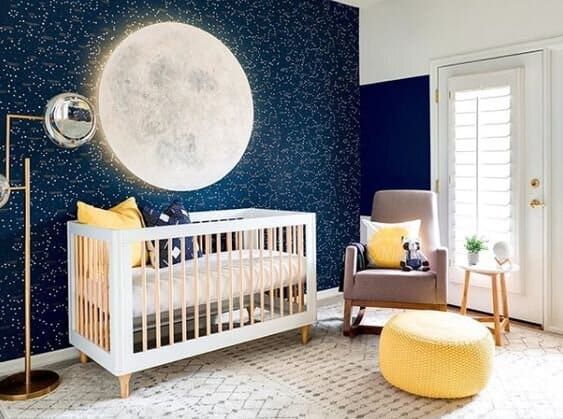 a baby's room decorated in blue and yellow with a moon on the wall