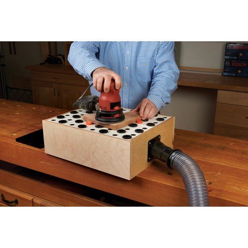 a person using a sanding machine on a piece of wood in a box with holes