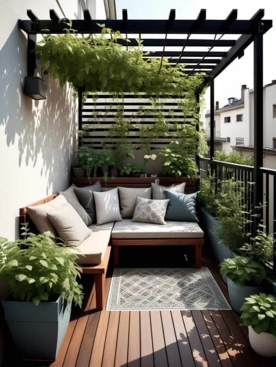 an outdoor seating area with potted plants on the side and wooden flooring in front