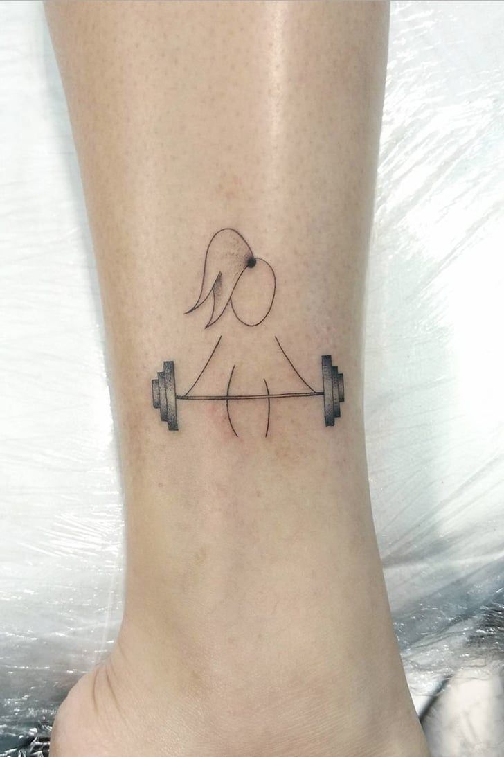 a woman's foot with a tattoo of a dog and barbells on it