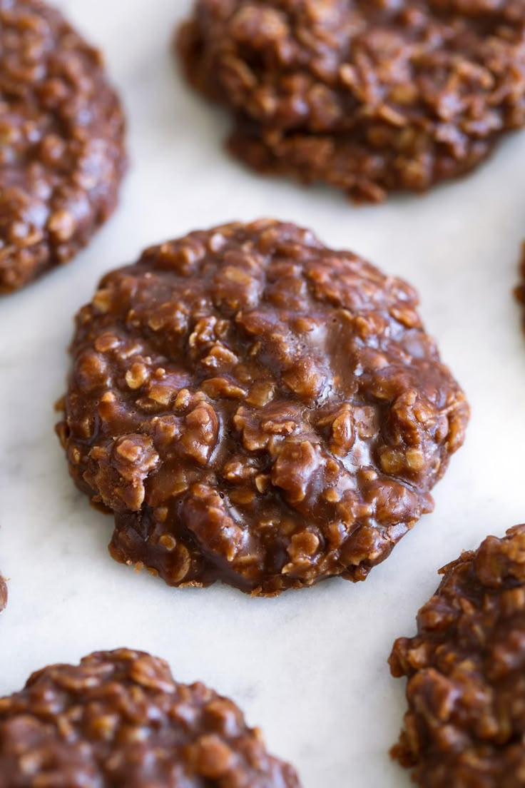 chocolate cookies are arranged in rows on a white counter top, ready to be eaten