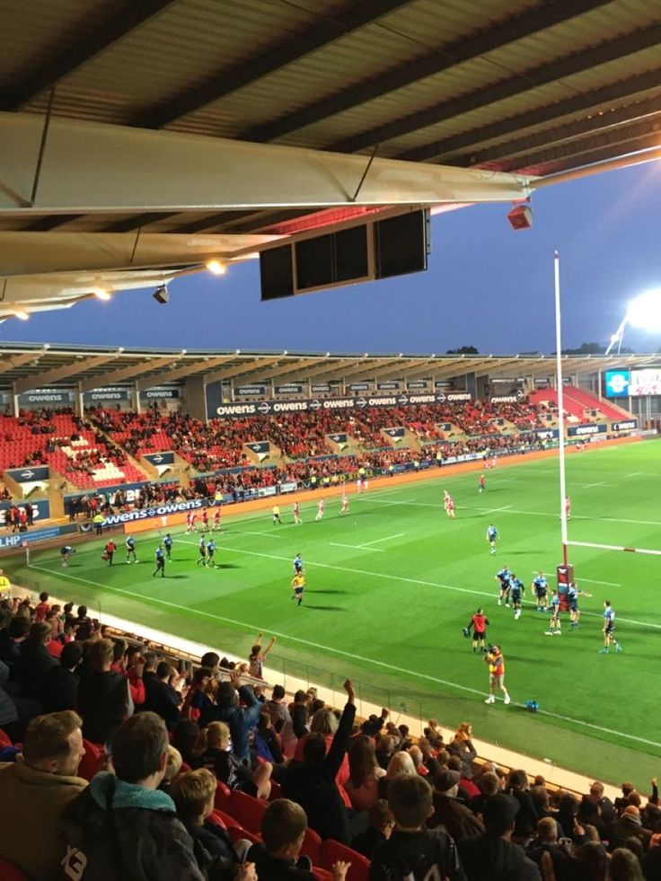 a group of people playing soccer on a field with fans in the bleachers