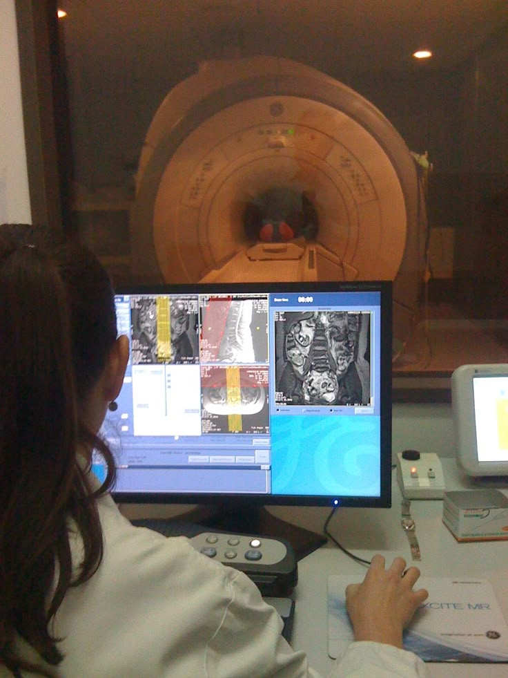 a woman sitting at a desk in front of a computer monitor with pictures on it