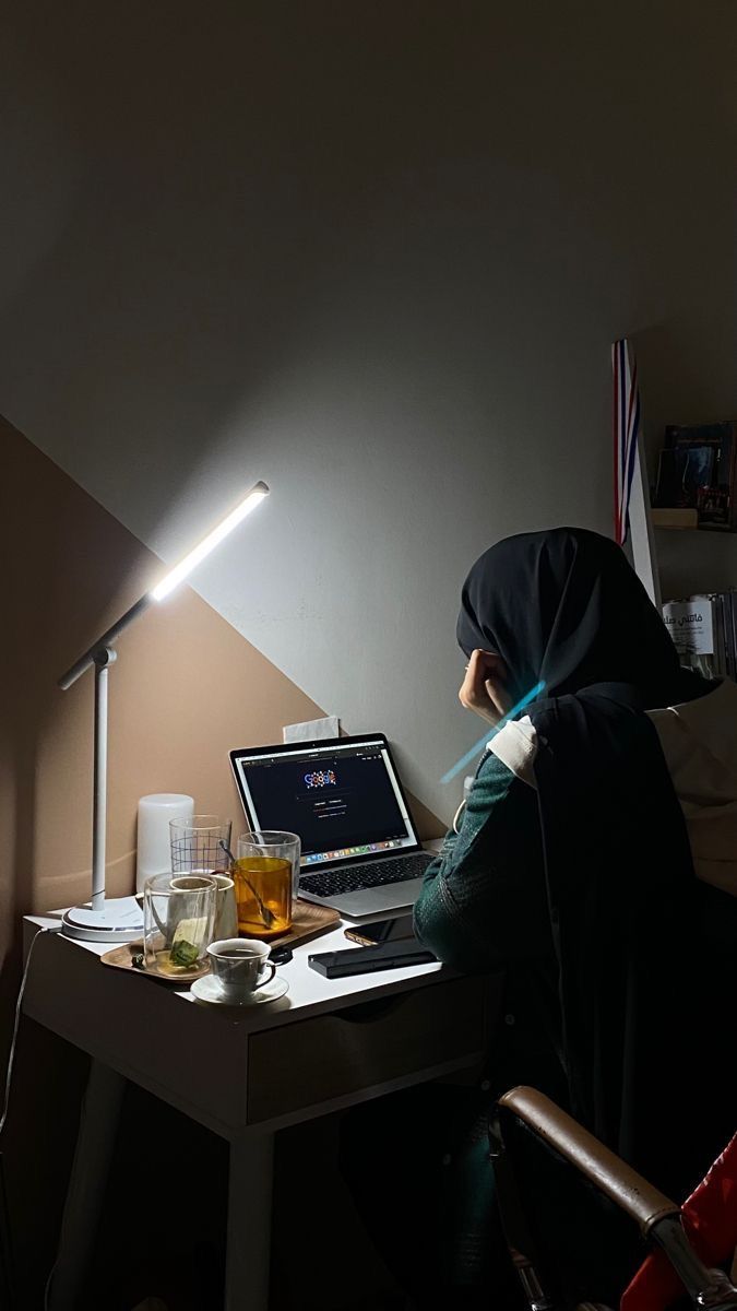 a person sitting at a desk in front of a laptop computer with a light on