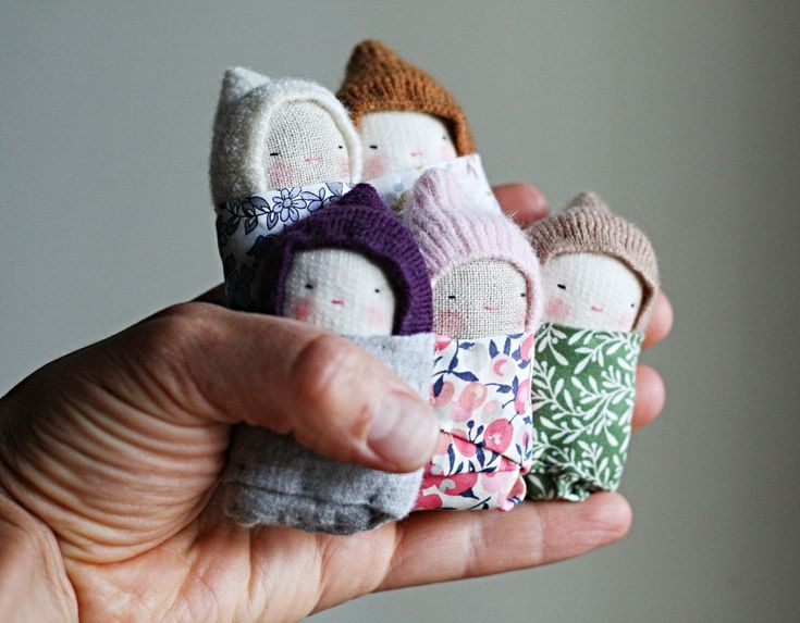 a hand holding several small dolls in different colors