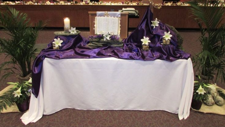 the table is set up with purple cloths and flowers on it, along with candles