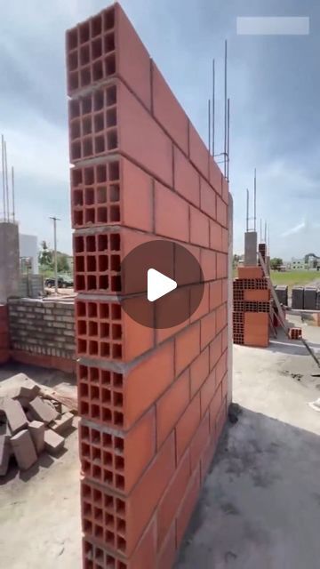 a red brick wall sitting on top of a cement floor next to a pile of bricks