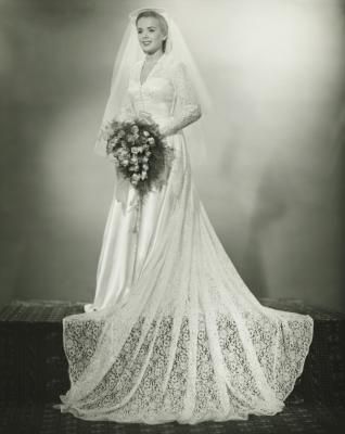 an old black and white photo of a woman in a wedding dress holding a bouquet