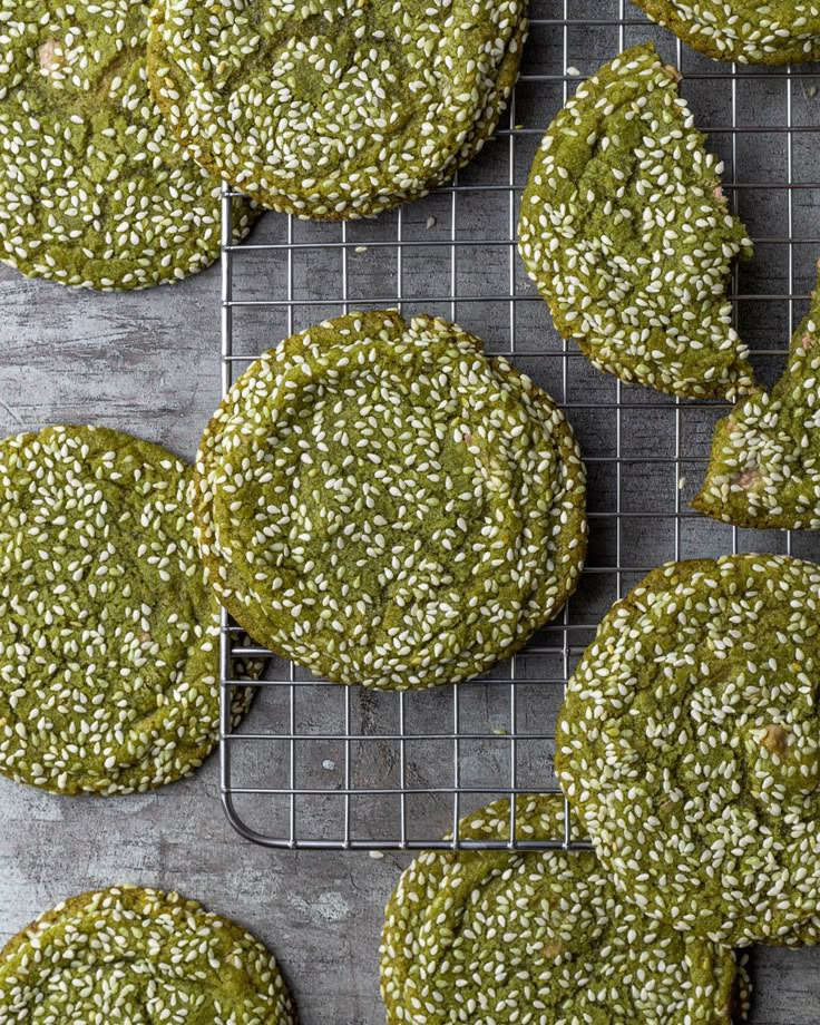 sesame seed cookies cooling on a wire rack with green glaze and sprinkles