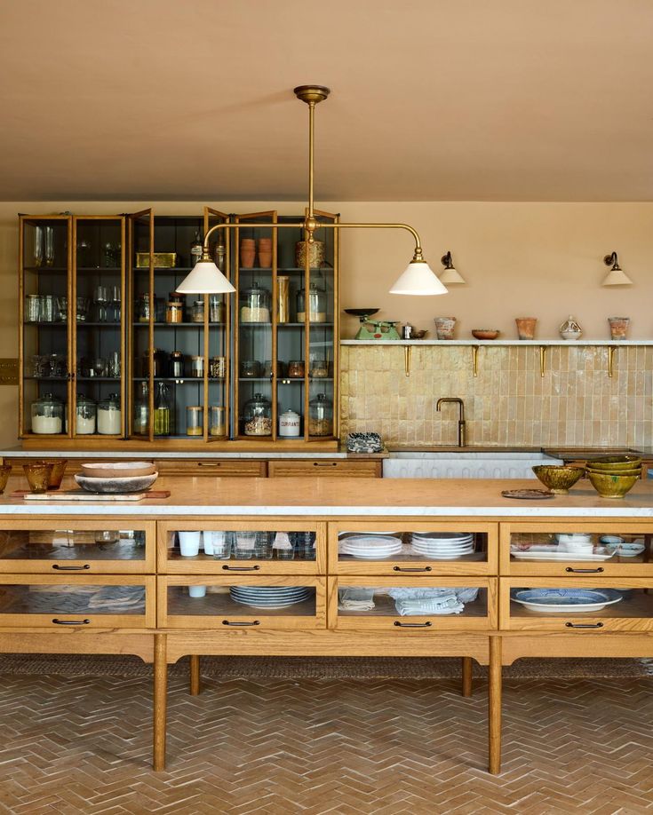 a kitchen with lots of wooden cabinets and white plates on the counter top in front of it