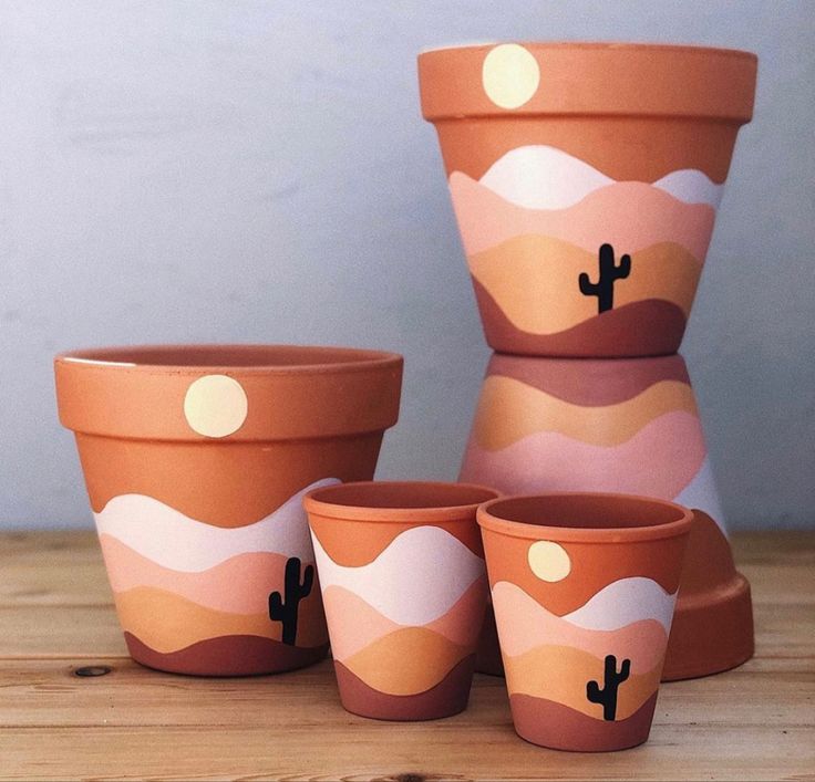 four pots with cactus designs on them sitting on a table